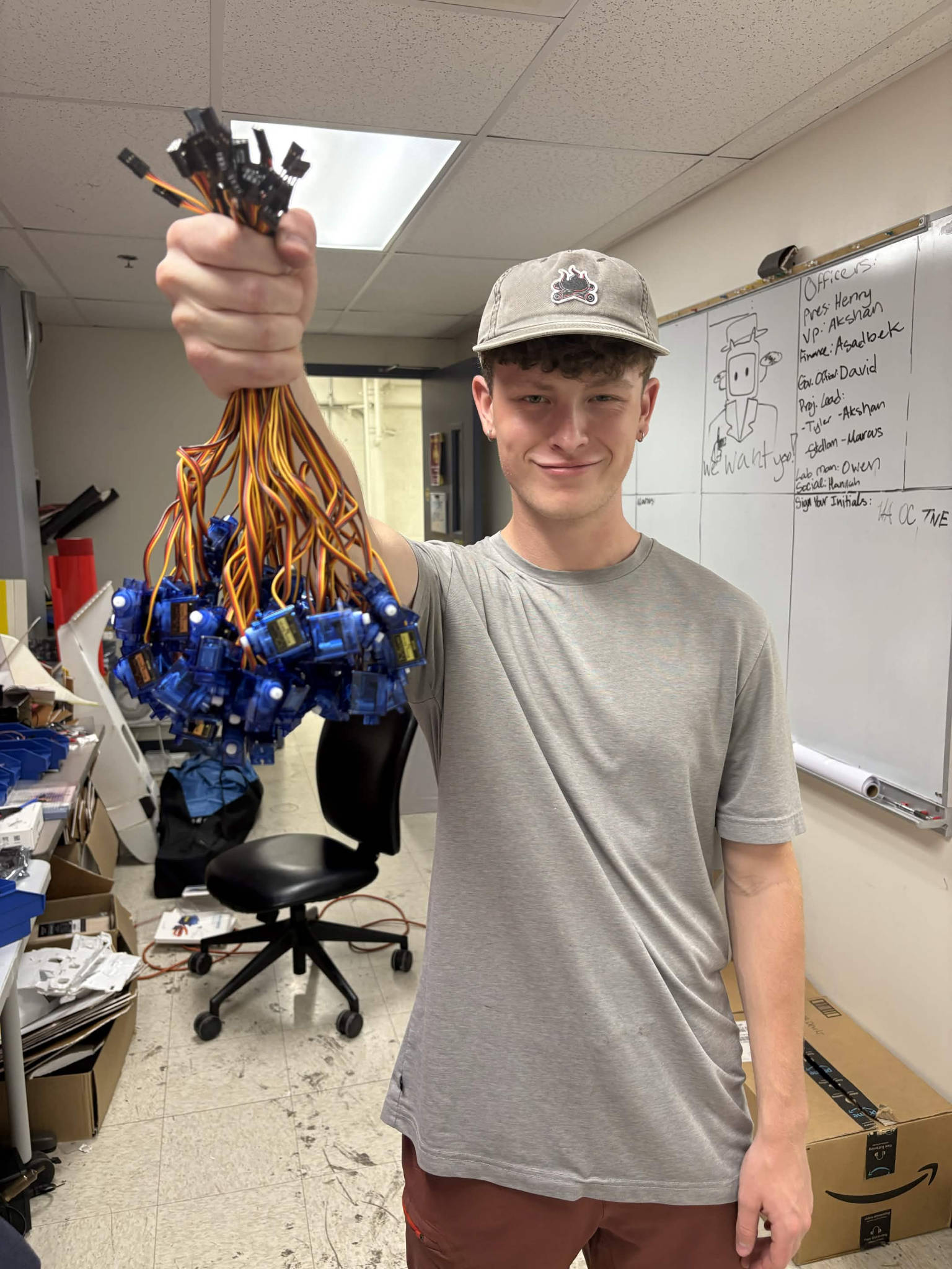 Club member holding a large bundle of blue micro servos in the lab